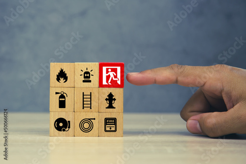 Hand choose wooden block stack with door exit sing or fire escape and fire prevent icon with fire extinguisher and emergency protection symbol for safety and rescue in the building.