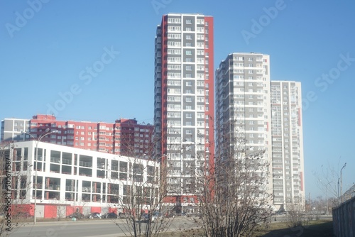 Full-color horizontal photo. An urban landscape with white building structures against a blue sky background.