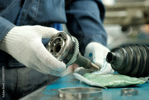 Car maintenance and repair in the car center. A joint of equal angular velocities in the hands of an auto mechanic. Inspection and control of the conformity and integrity of the spare part.