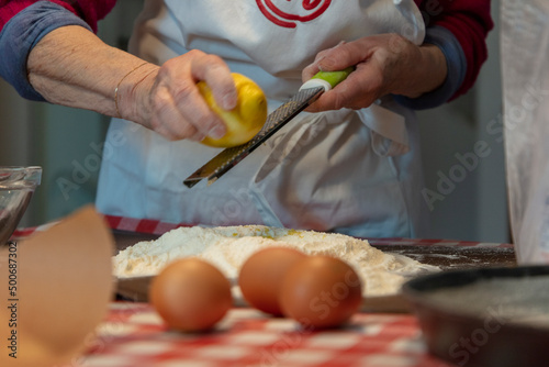 woman preparing a dough; making a cake; italian nonna grating a lemon for a crostata