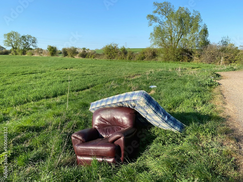 Fly tipped furniture in a grassy field. Landscape view.