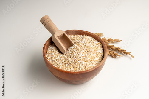 Spelt bran and grains in clay pot isolated on white background