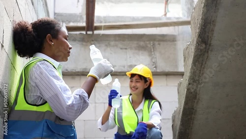 Diversity engineer woman teamwork and architect drinking water from bottle at construction site after calculate spending report projects. Real Estate Project with Civil Engineer
