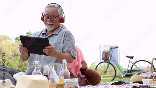 An elderly couple doing picnics and relaxing in the garden with bright smiles and enjoying the relaxation of classical music. Health and relaxation after retirement.
