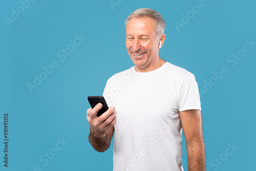 Mature man using his mobile phone wearing wireless earphones
