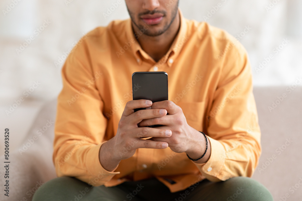 Young man using smartphone at home, close up Young man using smartphone at home, close up