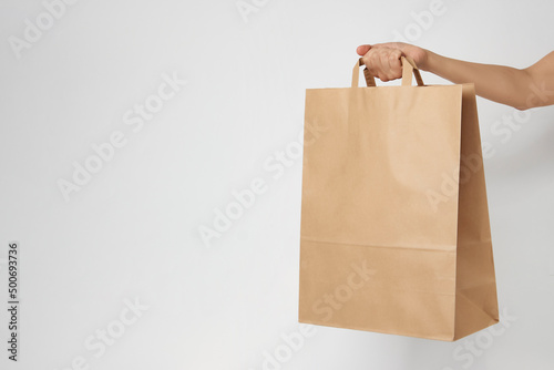 Woman holding brown paper bag on white background