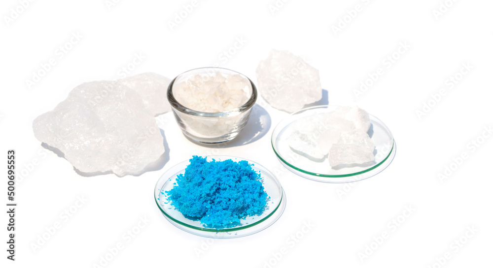Closeup inorganic chemical on white laboratory table. Copper(II) sulfate in Chemical Watch Glass. Alum Crystal and Flake salt were placed further away. Closeup inorganic chemical on white laboratory table. Copper(II) sulfate in Chemical Watch Glass. Alum Crystal and Flake salt were placed further away.