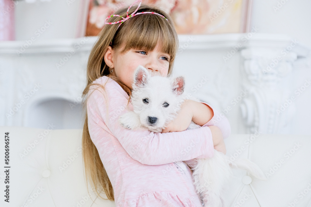 Child playing with West Highland White Terrier. Little girl hugging a puppy on the street. Child playing with West Highland White Terrier. Little girl hugging a puppy on the street.