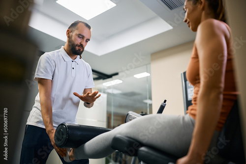 Fotografi Personal trainer assists sportswoman with her rehabilitation treatment at health club