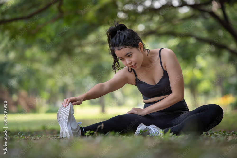 Young Asian woman doing stretching warm up before exercise outdoors in park, sport and healthy lifestyle concept Young Asian woman doing stretching warm up before exercise outdoors in park, sport and healthy lifestyle concept