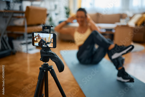 Close up of personal trainer recording exercise class for her vlog at home.