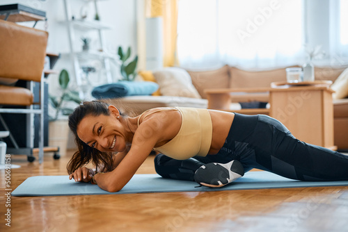 Happy athlete improving her hip mobility while stretching in pigeon pose.