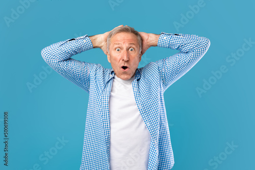 Canvas Print Surprised mature man grabbing head staring at camera