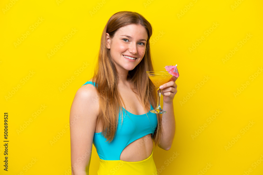 Young caucasian woman holding a cocktail isolated on yellow background smiling a lot Young caucasian woman holding a cocktail isolated on yellow background smiling a lot