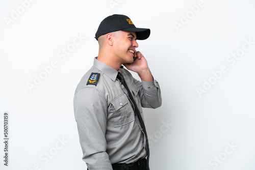 Young caucasian security man isolated on white background keeping a conversation with the mobile phone with someone