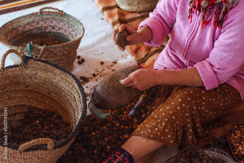 Fotografie Woman breaking argan seeds using a rock to make oil, in a cooperative in Morocco, real people doing real things