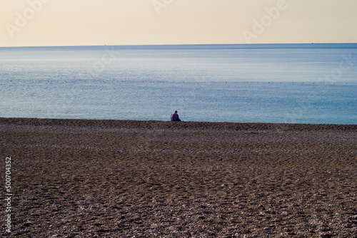 Fototapeta Naklejka Na Ścianę i Meble -  Lonely man sits on Antalya, Konyaalti beach and watches the sea.