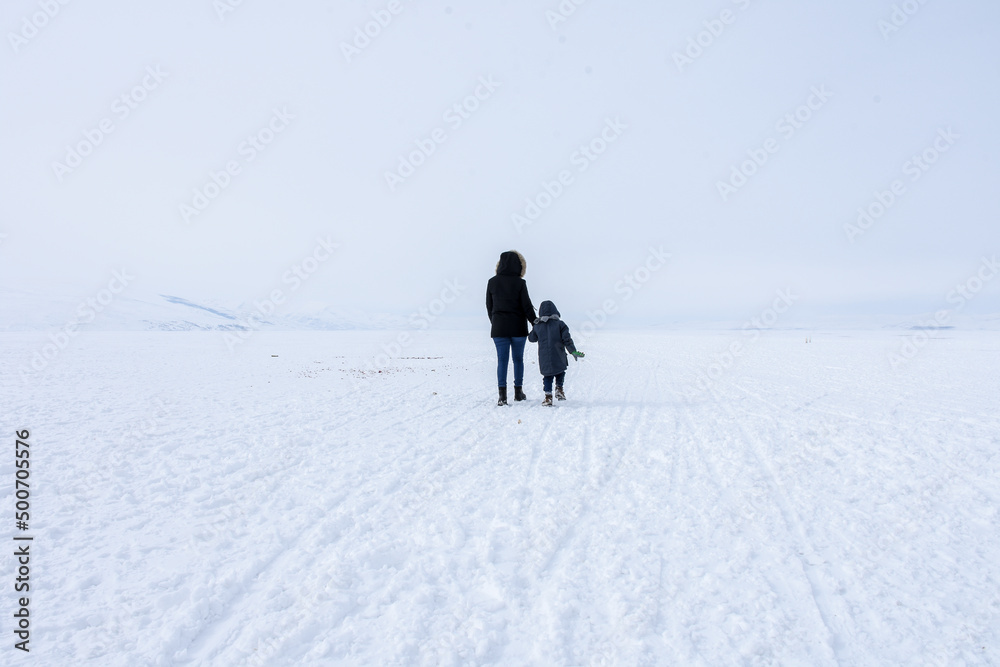 Woman and kid trekking walking on the frozen lake Çıldır in Ardahan Turkey