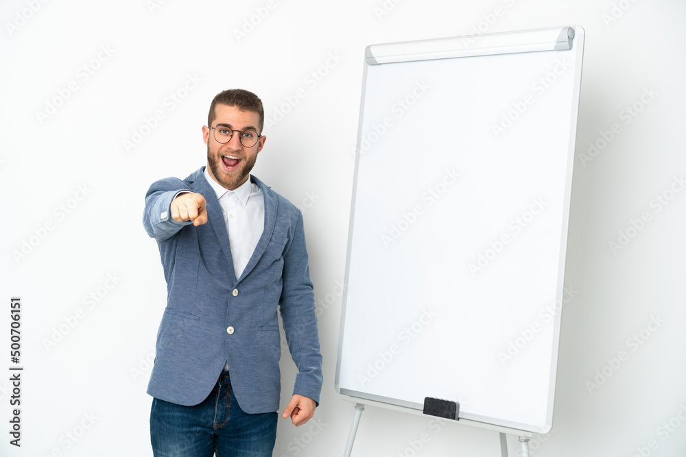 Young business woman giving a presentation on white board isolated on white background surprised and pointing front