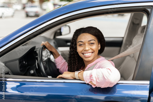 Smiling black woman driving new car in the city