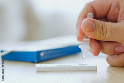 CLoseup hand using rapid antigen test kit (ATK) for self test at home. Dropping sample fluid on test kit. Pandemic of disease, covid-19, coronavirus photo