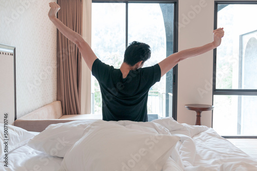 Man stretching in the morning after getting up. Man wake up and stretching in morning with sunlight by the window.