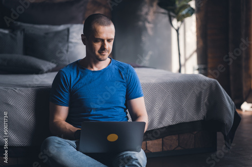 Adult man in blue t-shirt working on laptop