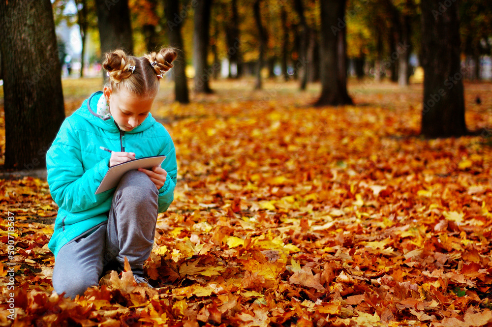 Autumn foliage. A girl among the yellow foliage draws