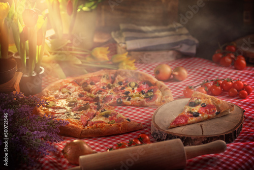 delicious and warm homemade pizza with salami and olives photo