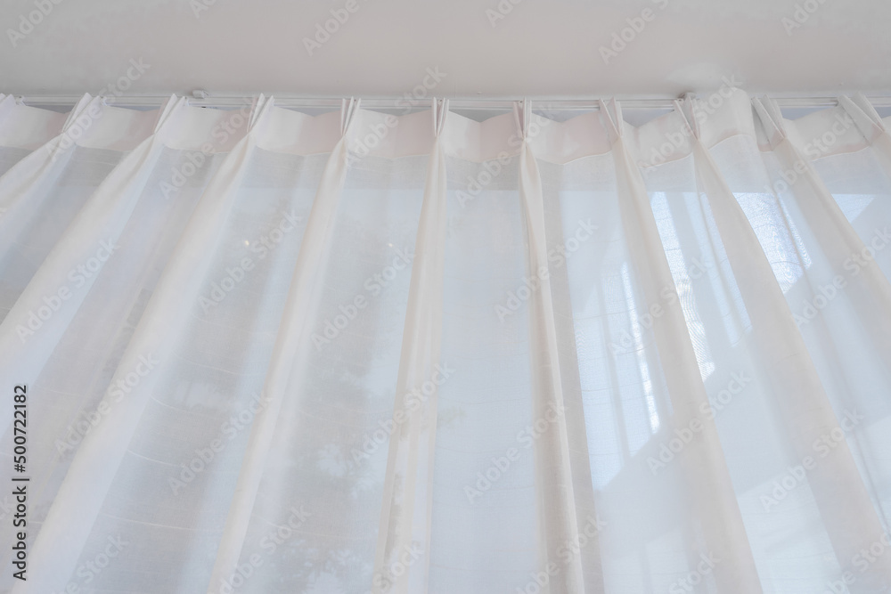 Beautiful translucent white fabric curtains in ripples with soft natural sunlight and see-through curtain balcony interior decorated the modern living room. Beautiful translucent white fabric curtains in ripples with soft natural sunlight and see-through curtain balcony interior decorated the modern living room.