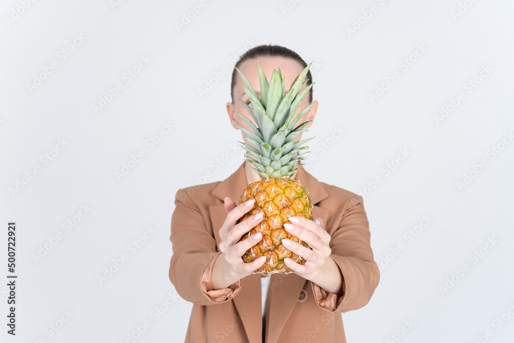 Obraz premium Close-up of hands with ripe honey pineapple. Unrecognizable woman in a beige jacket. Copy space on both sides of the banner.