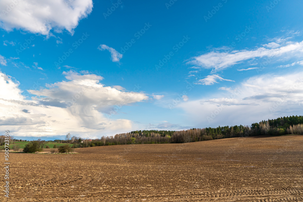 cloud movement over an agricultural field. A spring landscape with a forest, an empty field and clouds. The plowed field is ready for planting grain crops. cloud movement over an agricultural field. A spring landscape with a forest, an empty field and clouds. The plowed field is ready for planting grain crops.