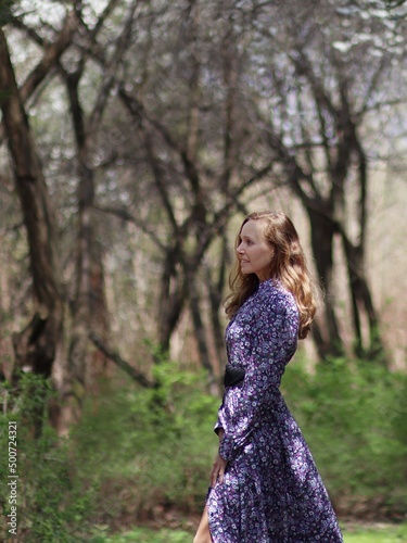Uśmiechnięta kobieta na spacerze w kwiecistej sukience z profilu