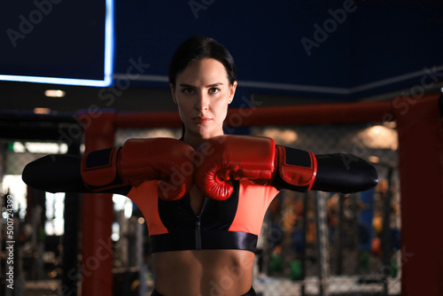 Young sports woman in tracksuit and putting hands together in red boxing gloves.