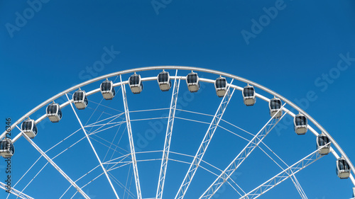Close-up details of ferris wheel on clear blue sky background  with metal beam guides and passenger booths. Marina Mall ferris wheel  Abu Dhabi  United Arab Emirates