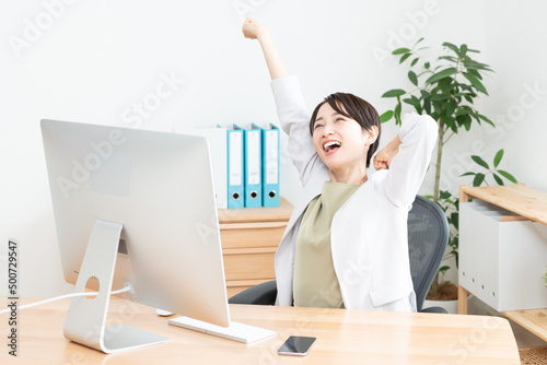 伸びをするオフィスで働く女性（ビジネス・ビジネスマン・ビジネスウーマン・OL・仕事・デスクトップパソコン） photo