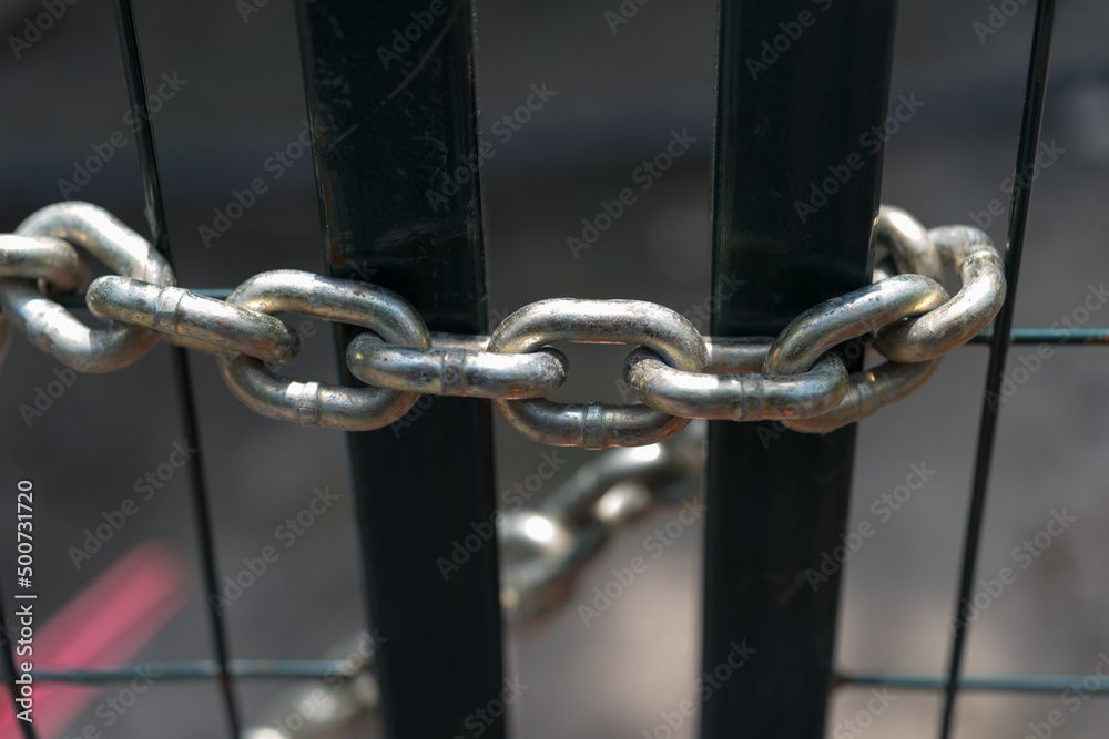 metal chain around bars of a metal fence metal chain around bars of a metal fence