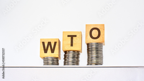 rising stacks of coins with the letters WTO on the wooden cubes, white background, business and finance concept photo