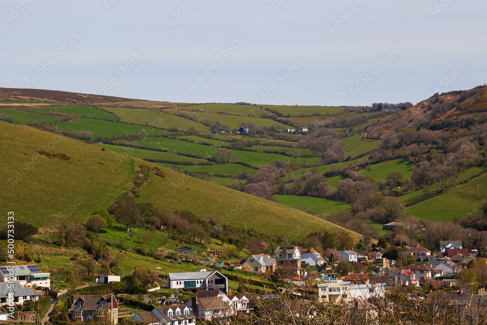 View of a beautiful village in a mountainous area with houses and manicured green fields