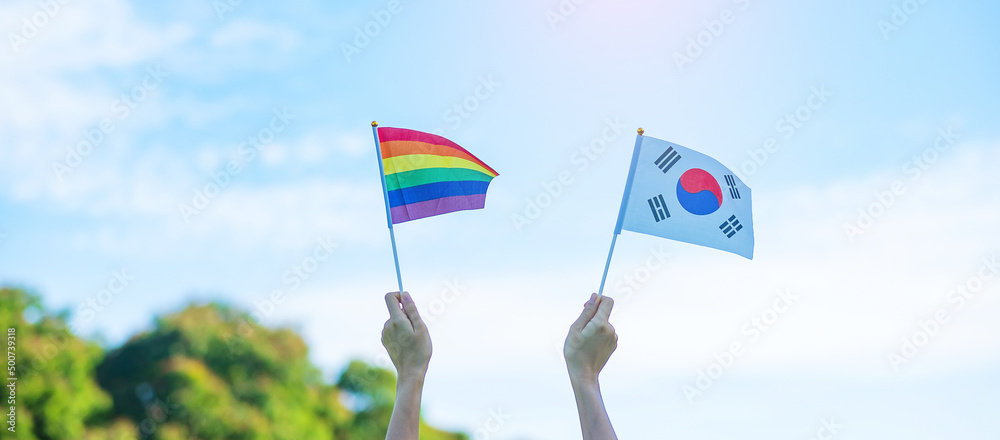 hands showing LGBTQ Rainbow and Korea flag on nature background. Support Lesbian, Gay, Bisexual, Transgender and Queer community and Pride month concept hands showing LGBTQ Rainbow and Korea flag on nature background. Support Lesbian, Gay, Bisexual, Transgender and Queer community and Pride month concept