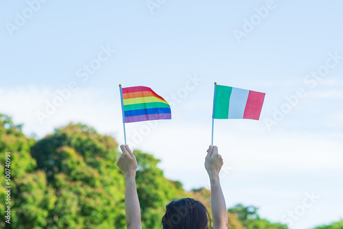 Photography hands showing LGBTQ Rainbow and Italy flag on nature background