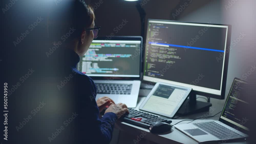 Young Asian woman, developer programmer, software engineer, IT support, wearing glasses working hard at nitght overtime on computer to check coding in bugging system. Back view