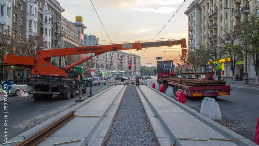 Orange construction telescopic mobile crane unloading tram rails from truck timelapse.