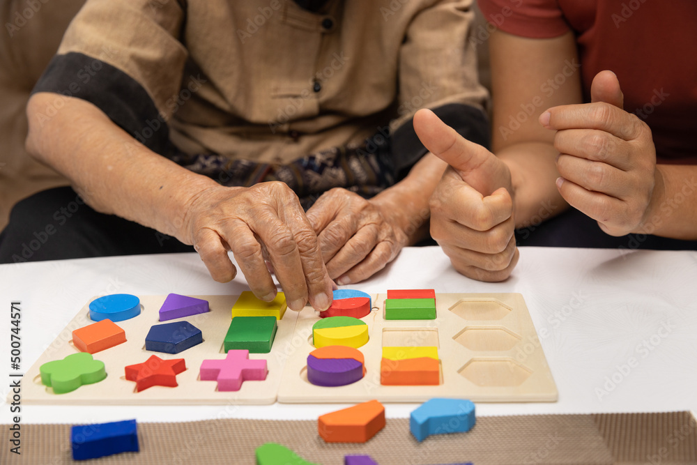 Caregiver and senior woman playing wooden shape puzzles game for dementia  prevention Photos | Adobe Stock