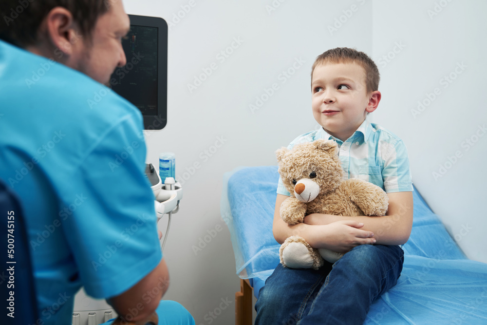 Caucasian young boy sitting with toy in doctor office Caucasian young boy sitting with toy in doctor office