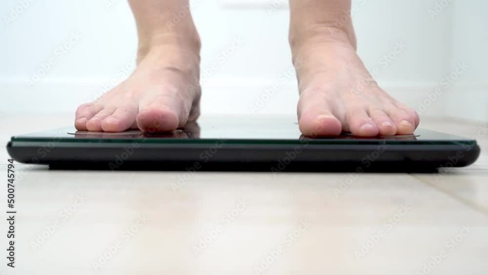 the girl standing on the scales, the concept of dieting. weight monitoring and measurement the girl standing on the scales, the concept of dieting. weight monitoring and measurement