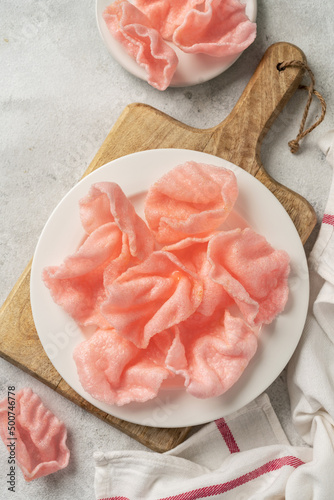 Shrimp chips in a white plate on a light cooking table. Krupuk udang in a plate on a culinary background