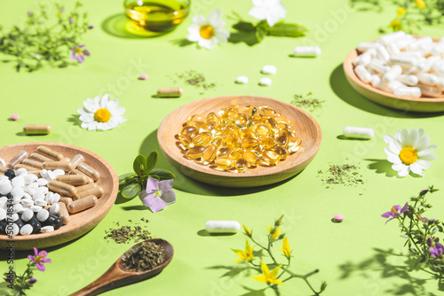 Фотография Diverse vitamin capsules and dietary supplements on green background