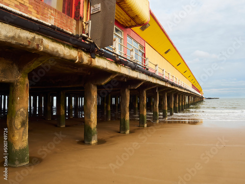 A fun fair complex on a pier, extending out into the sea at Frinton. The exposed, sea weed covered stanchions and cracking paint give a desolate feel. photo
